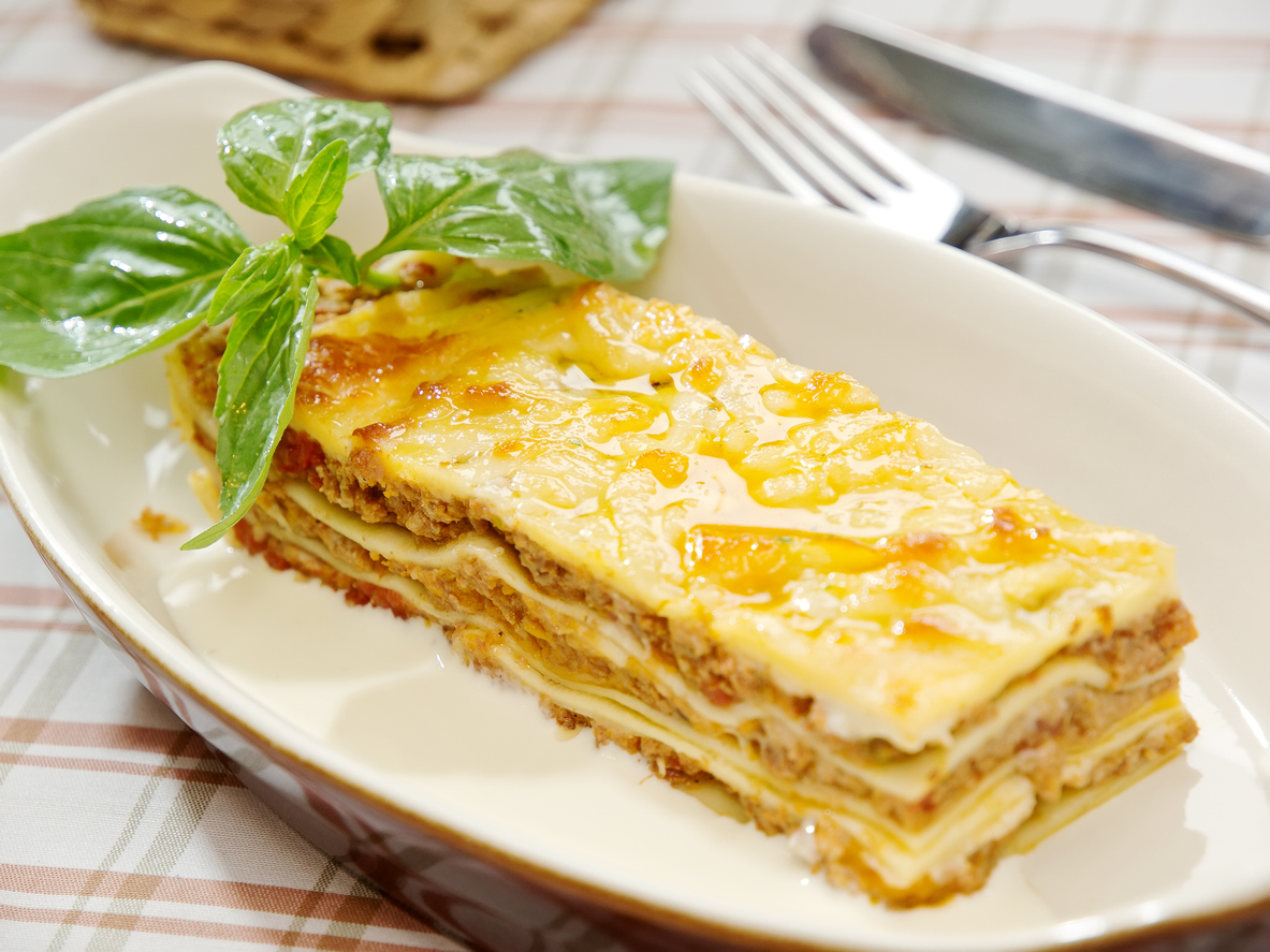 Portion Low-Carb-Lasagne garniert mit Basilikum auf einem Teller.