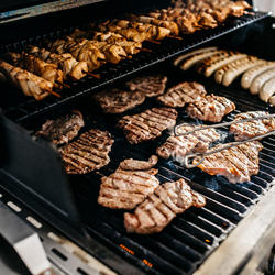 Grillplatte mit verschiedenen Fleischsorten und Würstchen.