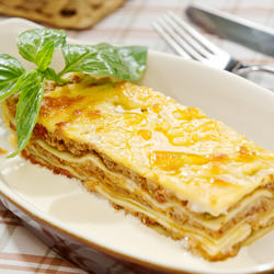 Portion Low-Carb-Lasagne garniert mit Basilikum auf einem Teller.